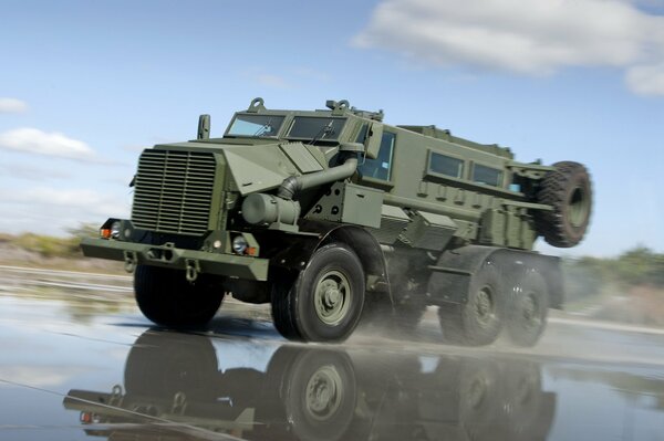 Military car on the background of a blue sky with clouds