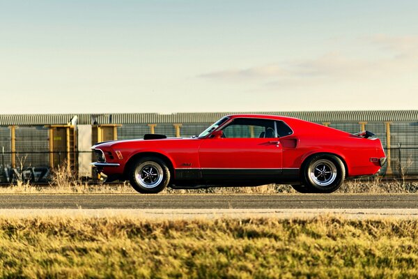 A red Ford Mustang is on the road