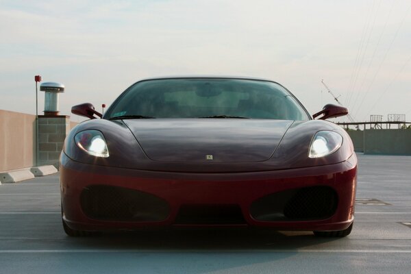 A burgundy Ferrari with headlights and eyes on the roof