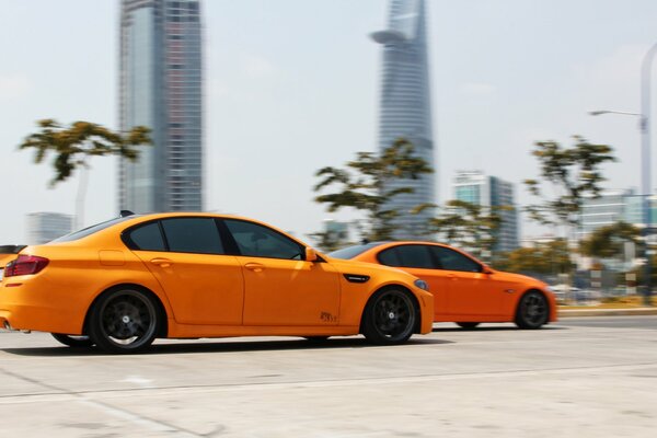 Dos coches de color naranja corren a alta velocidad por la carretera