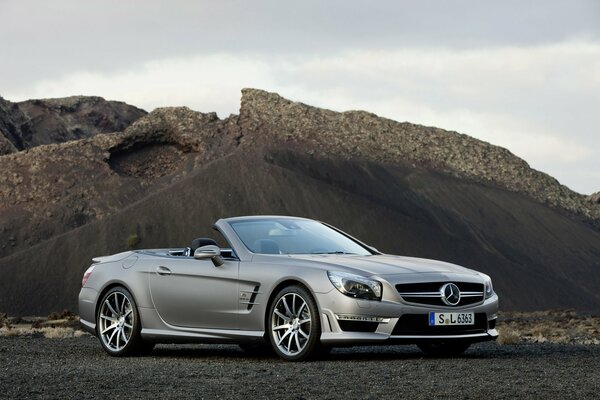The Mercedes-benz sl 63 amg car stands against the background of mountains and clouds