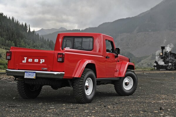 Jeep J-12 Pickup in rot Rückansicht auf dem Hintergrund der Berge