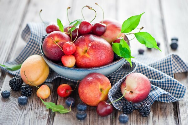 Berries and fruits in a bowl on a wooden table