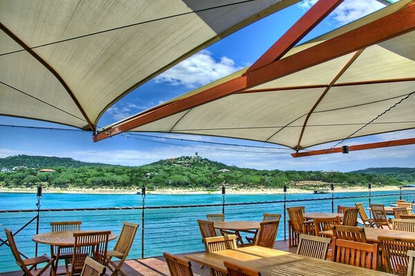 Awnings over the veranda on a background with a blue sea and an island
