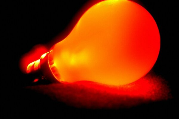 A red light bulb shines in the dark