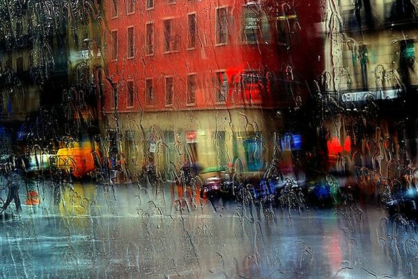 Vidrio en las gotas de lluvia en el fondo de la calle de la ciudad