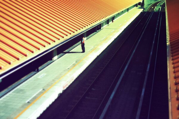 A man stands alone on a railway platform