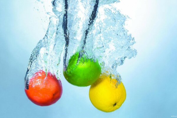 Three colorful apples are immersed in water