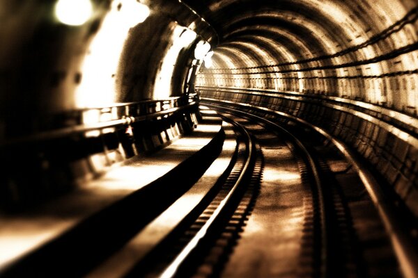 Retro photo of rails going behind the turn of the tunnel
