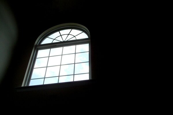 A tall semicircular window cutting through the darkness