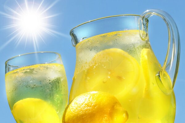 Lemonade with lemon in a jug against the background of the sun