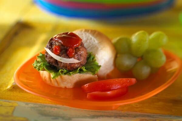 Sandwich avec brioche, tomates et ketchup, à côté des raisins