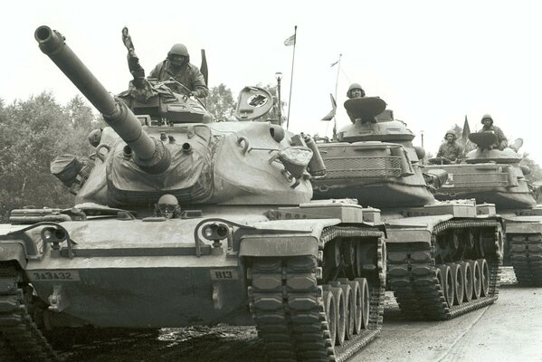 A row of moving tanks with soldiers