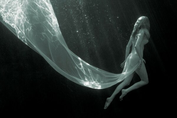 A girl in the depths of the water in a white dress