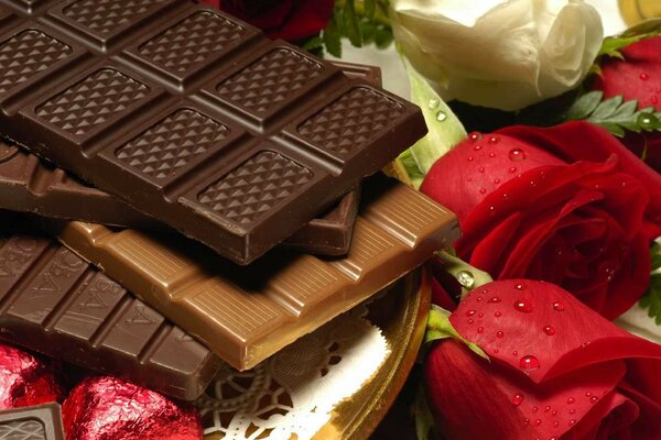 Tavolette di cioccolato su uno sfondo di rose rosse e bianche