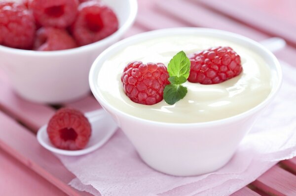 Молочный десерт с малиной в белой чашке