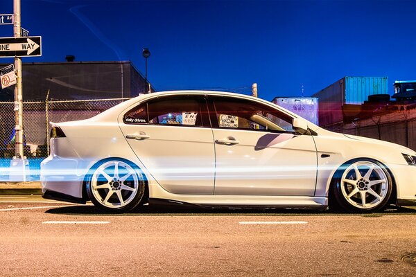 A white Jap car is parked near the ukozatel in the city