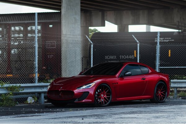 Maserati rouge inaccessible derrière le fil de fer barbelé