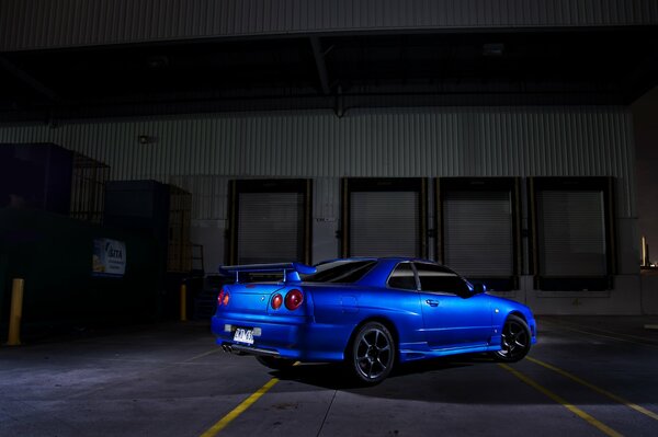 The blue nissan car comes out of the shadows