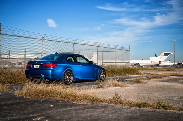 BMW blu su uno sfondo di guardrail e aerei 