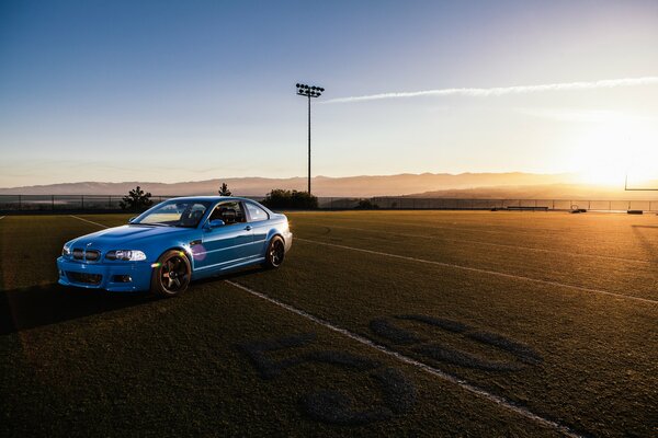 BMW de course bleue sur la route au coucher du soleil