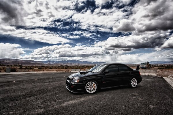 Black Subaru on a background of white clouds