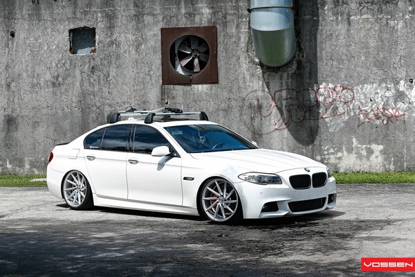 BMW blanco contra una pared gris