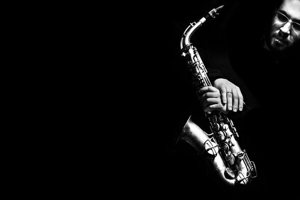 Saxofón en manos de un hombre sobre un fondo oscuro