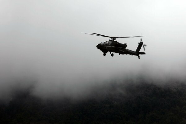 The helicopter flies over the abyss in the fog