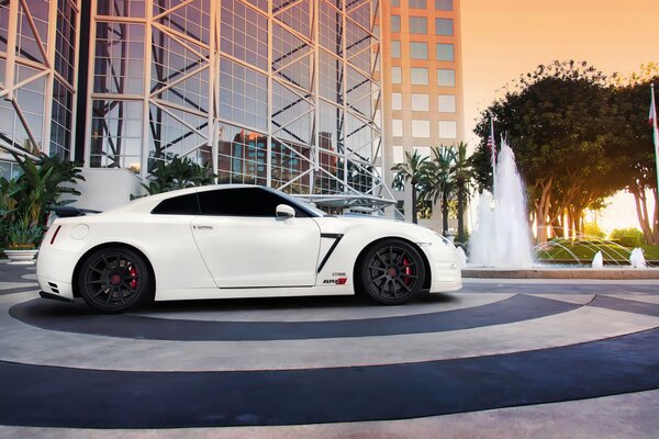 White Nissan car on the background of a tall building