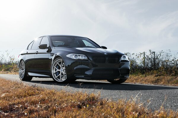 Vista frontal del BMW M5 negro entre el hermoso cielo