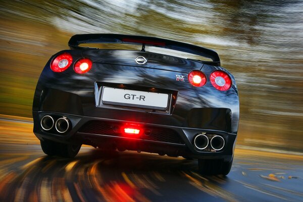 A black Nissan in motion on an autumn road