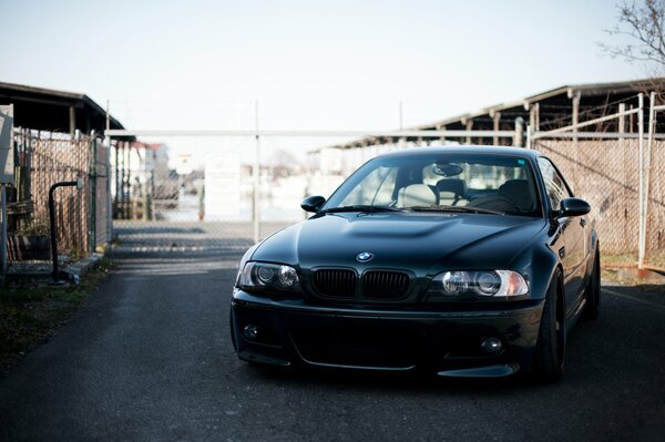 Black BMW on the road near the fence