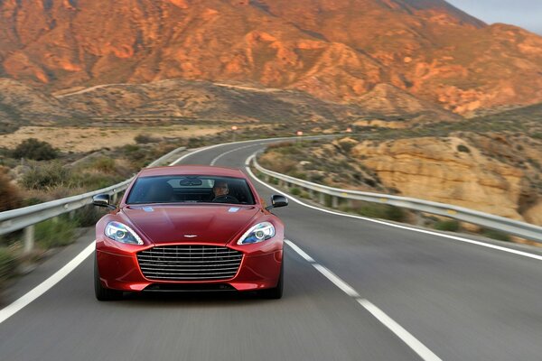 A red car is moving along the road. Front view