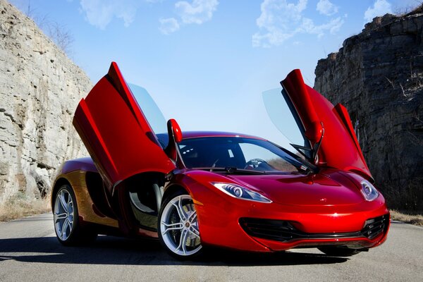 McLaren rouge entre les rochers sur fond de ciel bleu