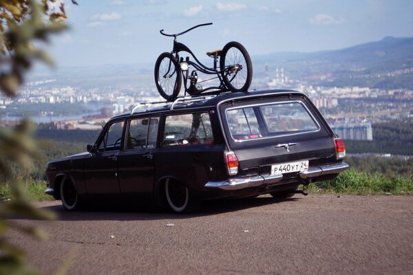 A rare Volga with a bicycle on the roof against the background of the city