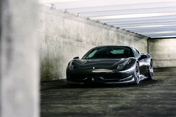 Une Ferrari noire garée contre un mur