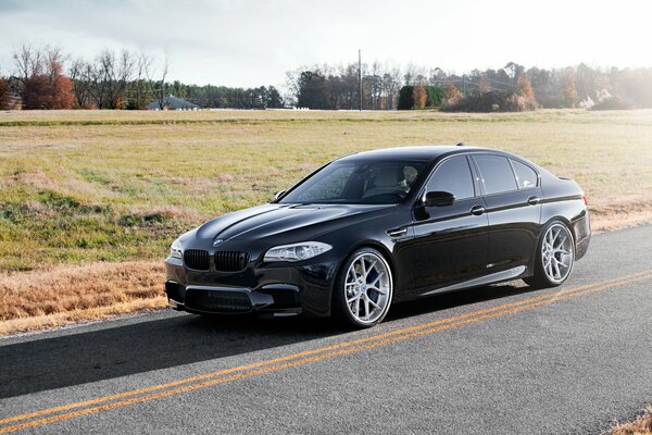 BMW F10 noire sur route de campagne