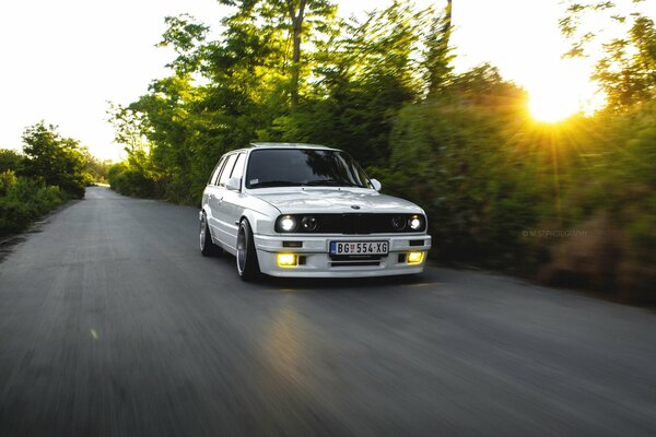 Weißes Auto bmw e30 auf Sonnenuntergang Hintergrund