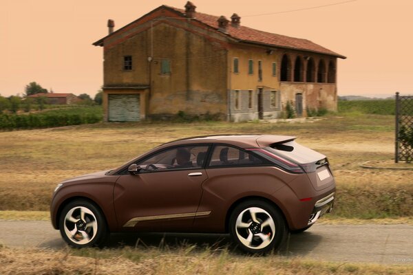 Brauner Lada Crossover in einem Feld vor einem verlassenen Haus