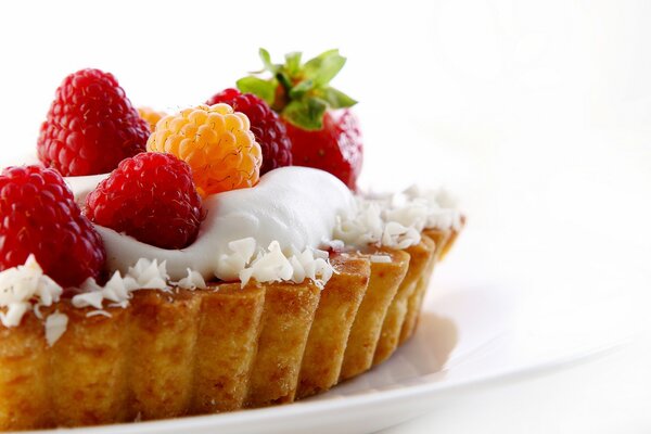 A cake with sweet cream, decorated with strawberries and raspberries, turns out to be a delicious dessert