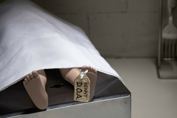 In the morgue, a body covered with a sheet and a tag on the leg