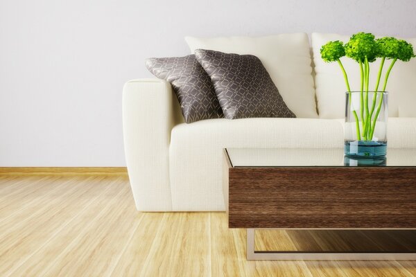 Coussins gris sur un canapé blanc et un vase sur une table