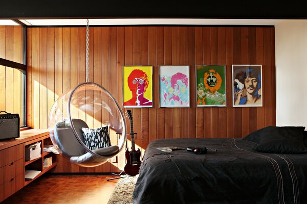 Portrety Beatlesów i wiszące krzesło we wnętrzu sypialni