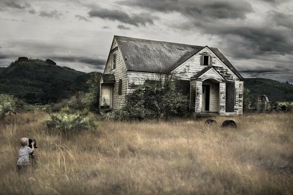 A boy on the grass takes pictures of the house