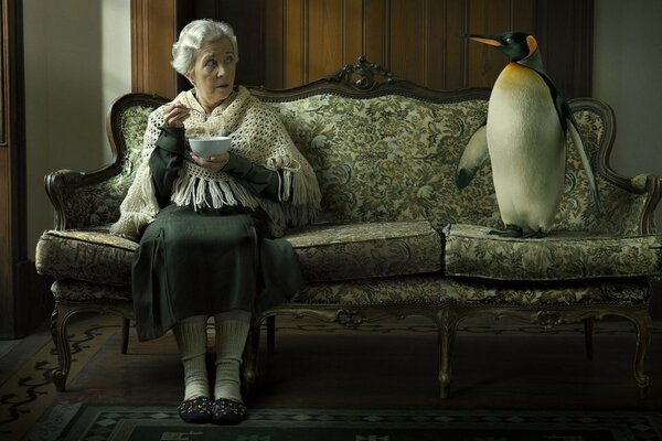 La abuela se sienta en el Sofá con un pingüino