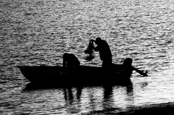 Pescadores en un barco recogiendo redes blanco y negro