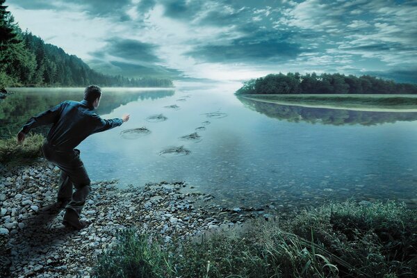 Człowiek rzuca kamieniami do rzeki przy lesie