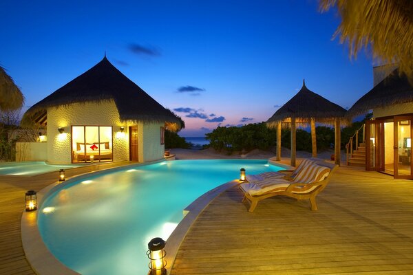 Noche junto a la piscina con iluminación y tumbona