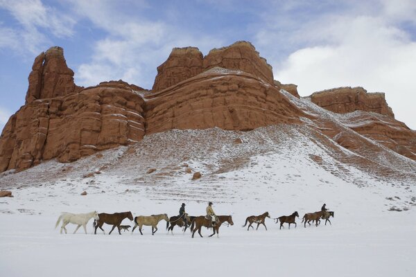 Los vaqueros destilan caballos en un sendero cubierto de nieve